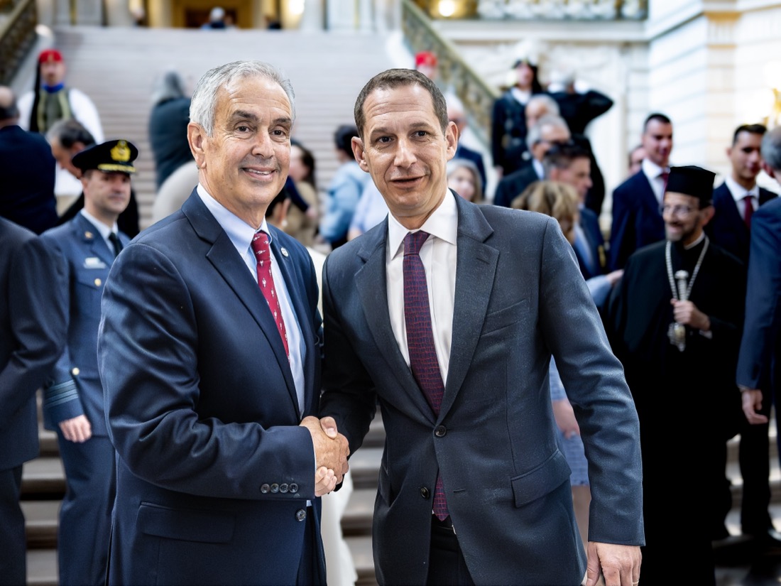 Taso Zografos shaking hands with a civic leader at a formal reception